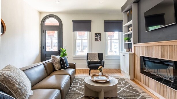Un salon moderne avec un canapé en cuir, une table basse ronde et une cheminée.