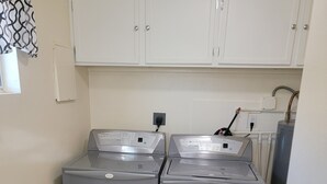 Une petite buanderie équipée de deux machines à laver à chargement frontal et de toilettes.