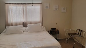 Une chambre à coucher comprenant un lit, un ventilateur de plafond, une table de chevet, une chaise et des œuvres d’art murales.