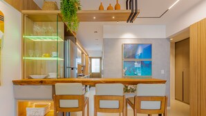 Una cocina moderna con armarios de madera, un expositor de vidrio y tres taburetes de bar.