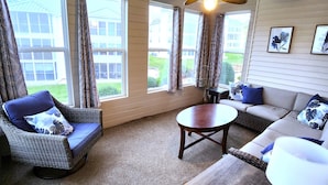 A room with a ceiling fan, large windows with curtains, a sofa, a chair, and a small table. - Walk In luxury condo with pools and hot tub! Comfy beds! (Branson)