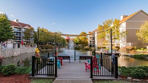 A courtyard with a pond, benches, and colorful chairs. - Walk In luxury condo with pools and hot tub! Comfy beds! (Branson)