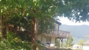 Una escalera de hormigón que sube hacia una casa rodeada de rocas y follaje.