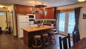 Una cocina con armarios de madera, una isla central con taburetes, un refrigerador y un microondas.