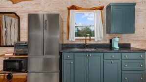 A compact kitchen with a built-in refrigerator, a microwave, a toaster oven, and a sink with a faucet. - The Hendo - Cabin #1 - Studio Style (Henderson)