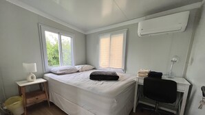 Une chambre à coucher avec un lit, un bureau, une chaise et une fenêtre.