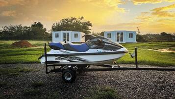 A Yamaha WaveRunner jet ski on a trailer in a grassy field with a small white building in the background.