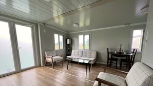 Un salon spacieux doté d’un plancher en bois, d’un canapé, d’un fauteuil et d’une table à manger avec des chaises.