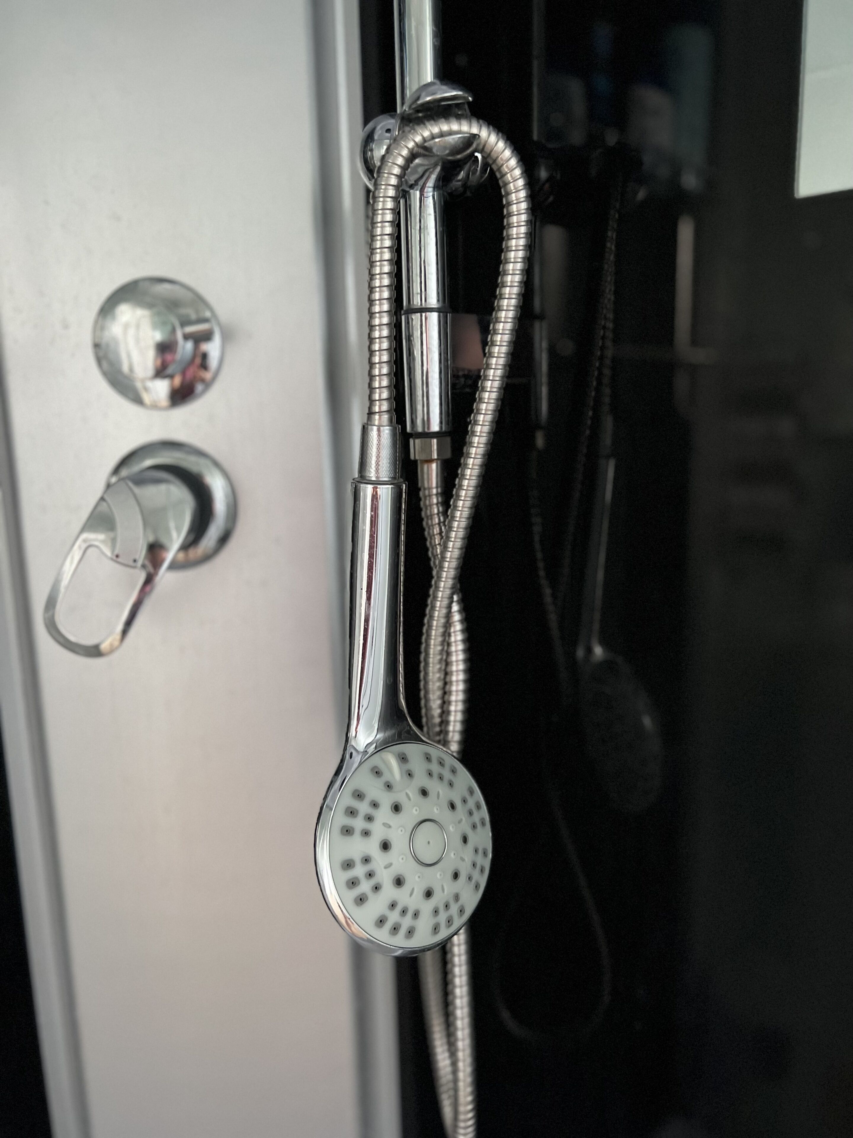 A shower with a flexible hose and a handheld showerhead.