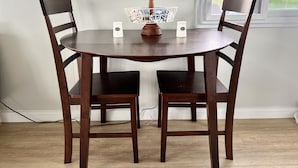 Une table ronde en bois, accompagnée de deux chaises, d’un salier et d’un poivrier, et d’un objet décoratif posé sur la table.