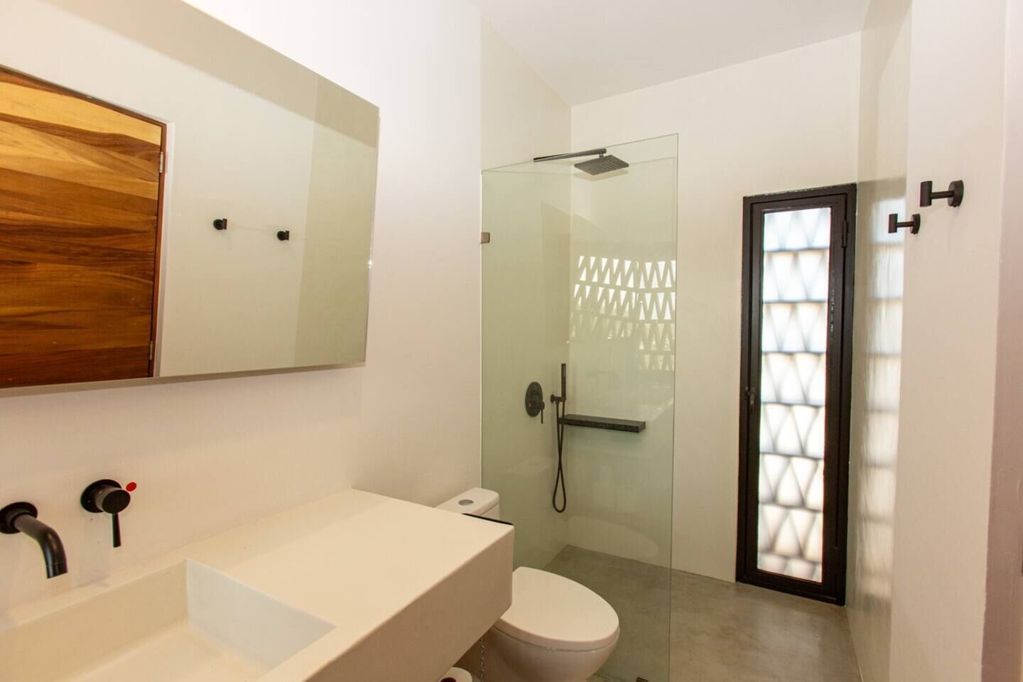 A modern bathroom with a large white sink, a glass shower enclosure, and a toilet.
