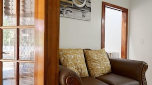 A brown leather sofa with patterned cushions, a wooden-framed window, and a wall-mounted abstract painting. - Located on Paradise Island, Bahamas, close to the Atlantis Resort and beach.  (Nassau)
