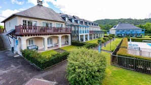 Una hilera de casas de dos pisos con balcones, una piscina y un jardín bien cuidado.