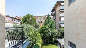 A courtyard with a small lawn, a metal railing, and a building with balconies.