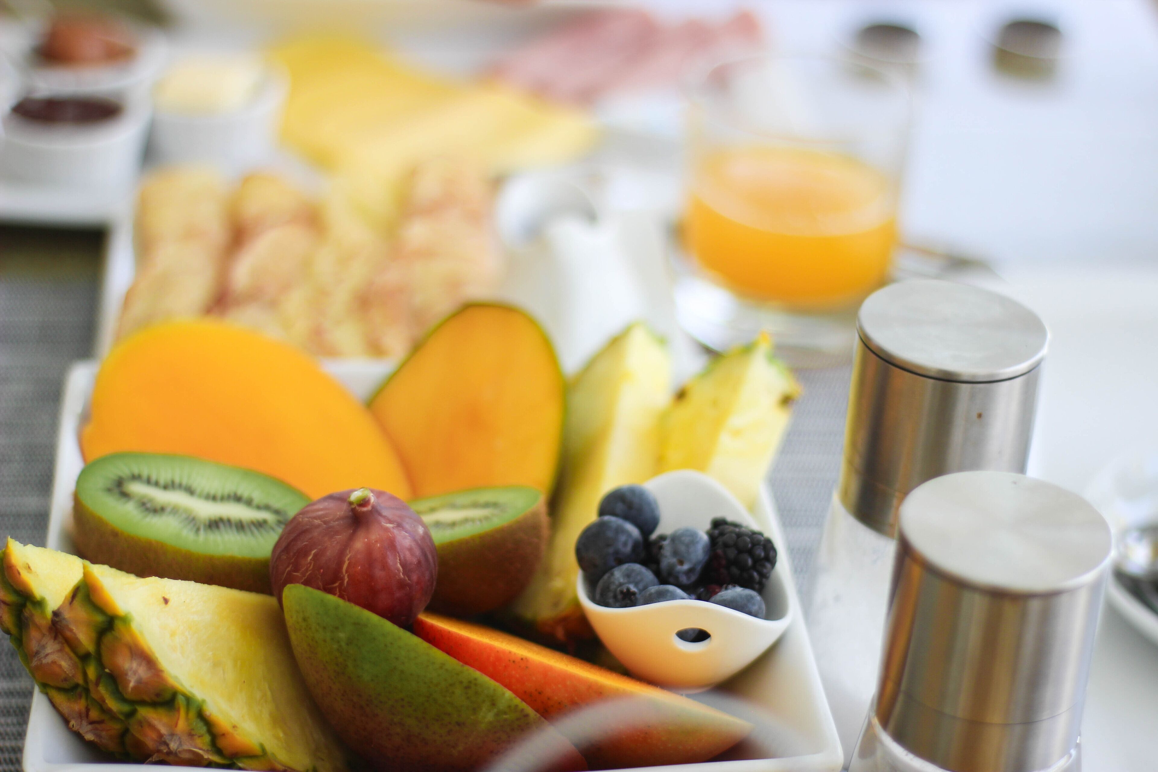 A fruit platter with various fruits and a salt shaker.