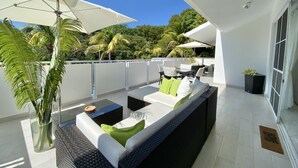 Un área de estar al aire libre moderna con sofá, cojines y una mesa.