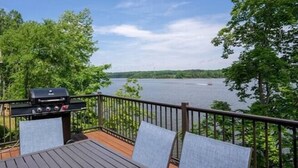 Une terrasse avec un barbecue et des chaises, donnant sur un lac.