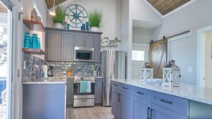 Une cuisine moderne avec des meubles gris, des appareils en acier inoxydable et un grand îlot central.