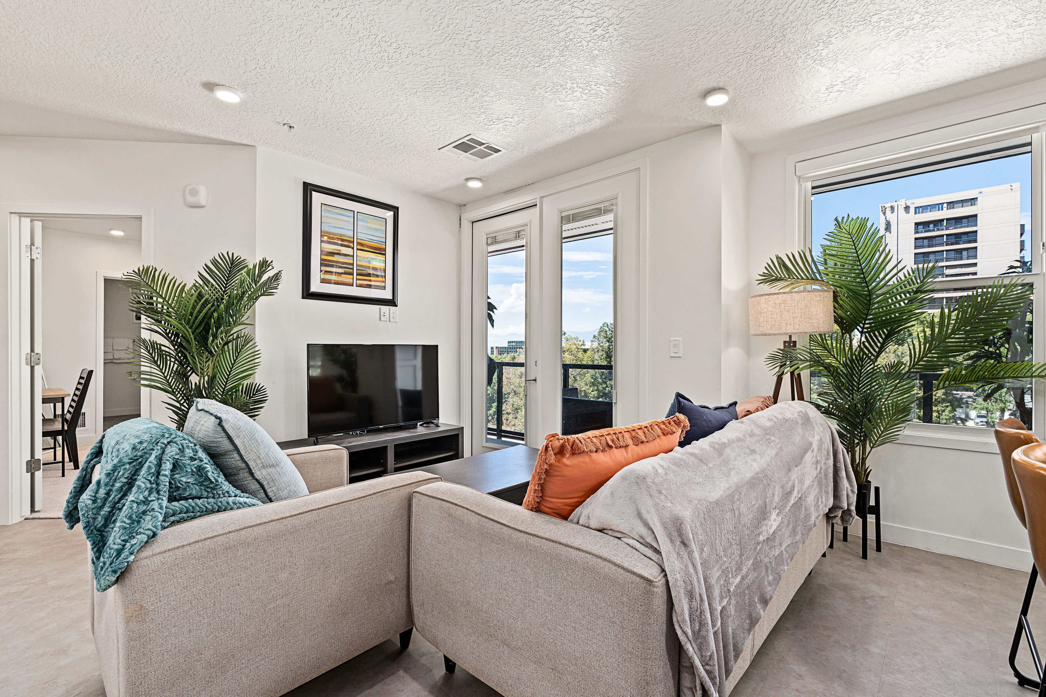 A modern living room with a sofa, a TV, and a dining area with chairs.