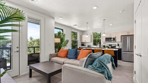 A modern living room with a sofa, coffee table, and a view of the kitchen. - Luxury Apartment in Salt Lake City (Salt Lake City)
