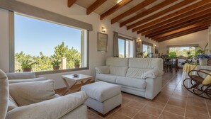 A spacious living room with a high ceiling, large windows, and a view of the outdoors.
