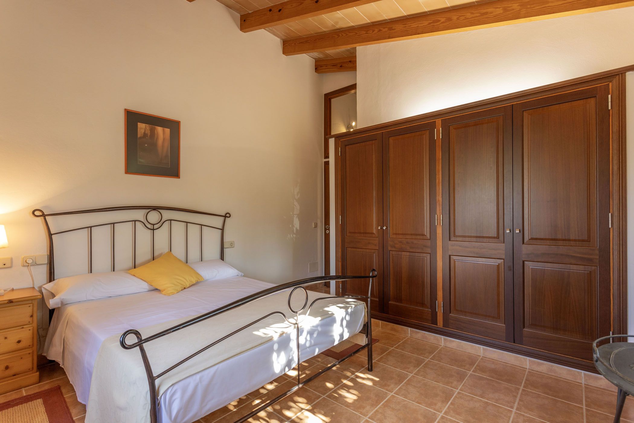 A bedroom with a bed, a wooden wardrobe, and a nightstand.