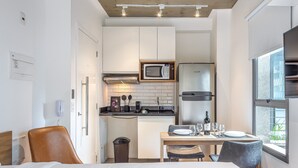 Et kompakt hotelværelse med tekøkken, spiseplads og seng.
