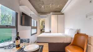 Et moderne hotelværelse med en seng, et spisebord med tallerkener og glas, en vinflaske og en læderstol.
