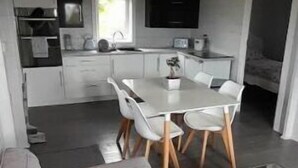 En moderne stue med en grå sofa, et glasbord og et spiseområde med et hvidt bord og stole.