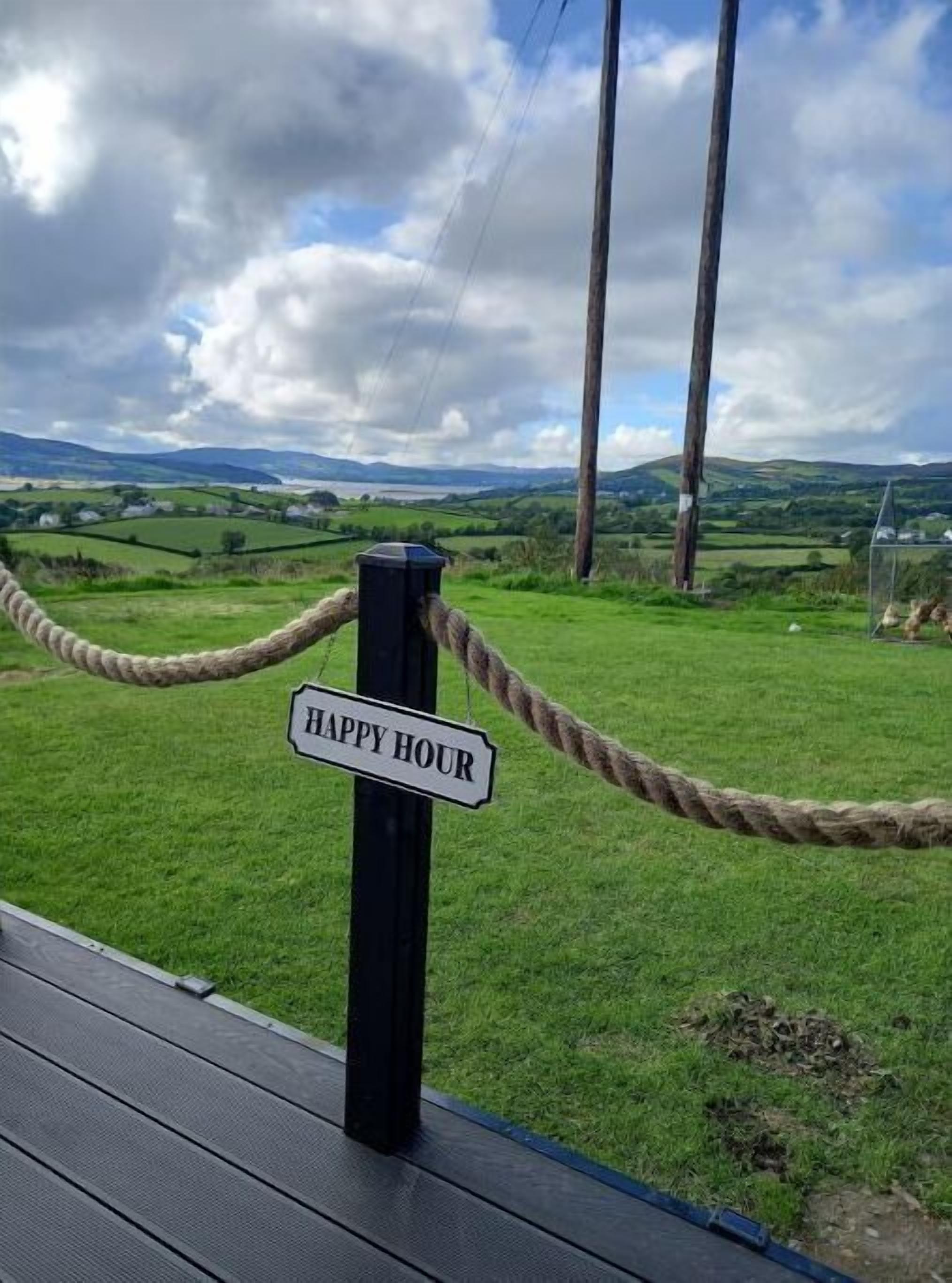 A rope barrier with a sign that reads "HAPPY HOUR" in a scenic outdoor setting.