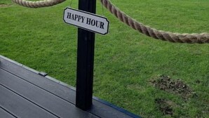 En rebsnor-spærring med et skilt, der siger "HAPPY HOUR" i et naturskønt udendørs miljø.