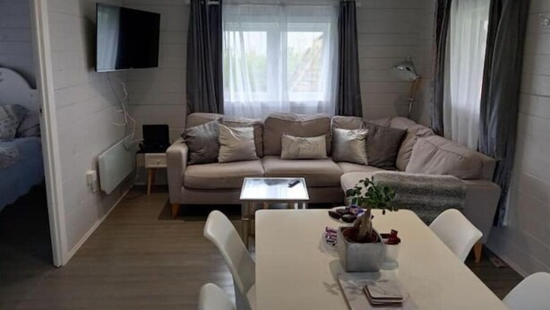 En hyggelig stue med en sofa, et sofabord og et fjernsyn monteret på væggen.