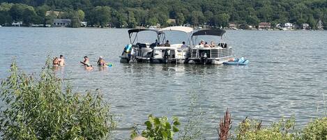 A lake with boats and people swimming.