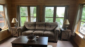 Ein gemütliches Wohnzimmer mit einem braunen Ledersofa, einem Holztisch und zwei passende Nachttische mit Lampen.