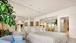 Ein modernes Schlafzimmer mit einem großen Bett, einem blauen Sessel und einem Spiegel, der den Raum wiederspiegelt.