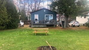 A blue house with a deck, a picnic table, and a fire pit in the yard. - Staying by the Lakeside Cottages (Plummer Additional)