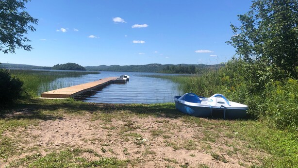 A wooden dock extending into a calm lake, with a small boat docked at the end. - Staying by the Lakeside Cottages (Plummer Additional)