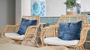 Wicker chairs with cushions and woven baskets on a patio. - Oceanfront Cocoa Beach Home | Direct Beach Access | Tiki Bar & Fire Pit (Cocoa Beach)