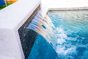 A pool with a waterfall feature, a tiled edge, and a brick pattern at the bottom. - Casa del Sol: Luxury Heatable Pool with Private Guest House (Laredo)