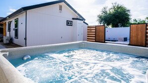 A hot tub area with a pool, a white building, and a wooden fence.