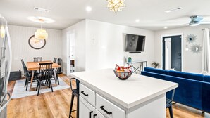 A modern kitchen with white cabinetry, a central island, and a blue sofa in the living area.