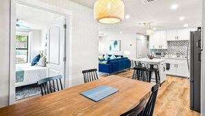 A modern kitchen with white cabinets, a black refrigerator, and a wooden dining table.