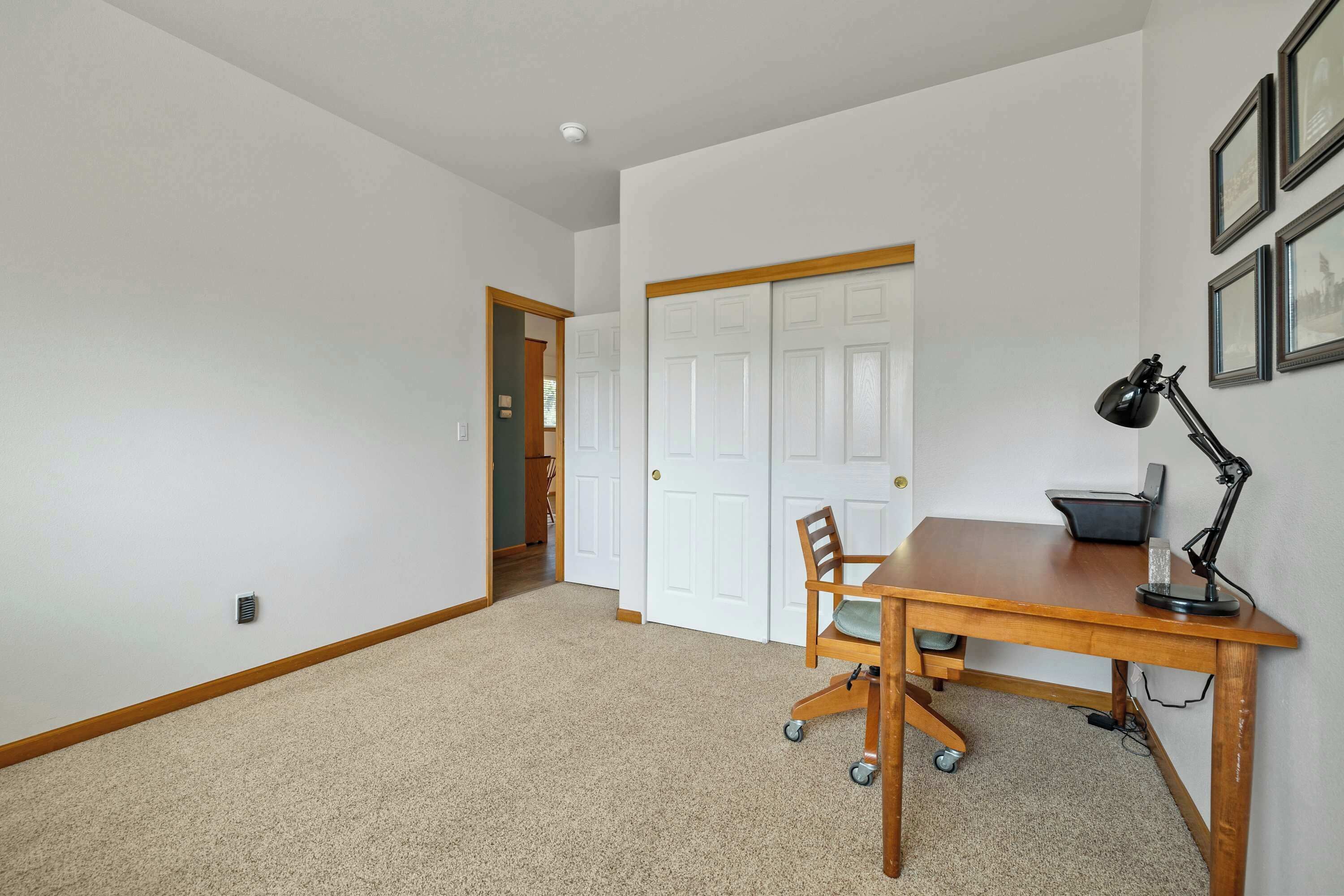 A room with a wooden desk, a chair, a lamp, and a door.