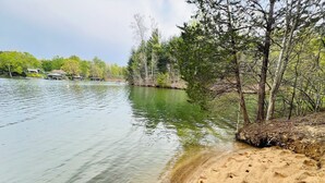 Un lago con acque limpide, una riva sabbiosa e alberi.