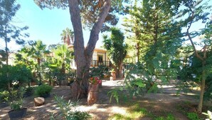 A garden with trees, a building with a balcony, and a paved walkway. - Caparica, V4 House with garden in Lazarim, Caparic (Caparica)