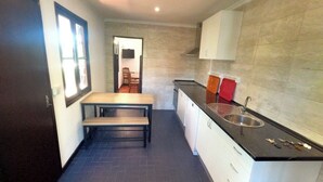 A compact kitchen with a dark floor, a dining table, a sink, and cabinets. - Caparica, V4 House with garden in Lazarim, Caparic (Caparica)