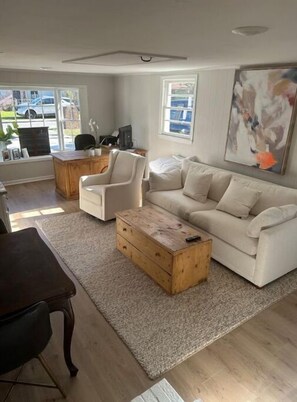 Relax in this stylish living room with a sofa, coffee table, and armchair, featuring a large window with a city view.