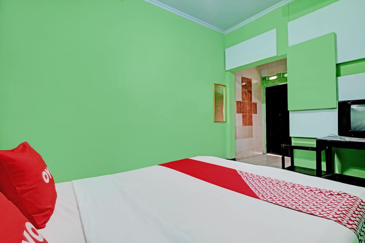 Een hotelkamer met een bed, een televisie en een deur naar een andere kamer.