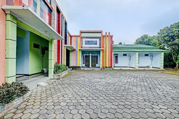 A building with a colorful facade, a paved courtyard, and a green roof. - OYO 92605 Hotel Las Vegas (Getasan)