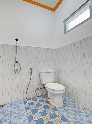 A bathroom with a toilet, shower, and patterned floor tiles. - OYO 92605 Hotel Las Vegas (Getasan)